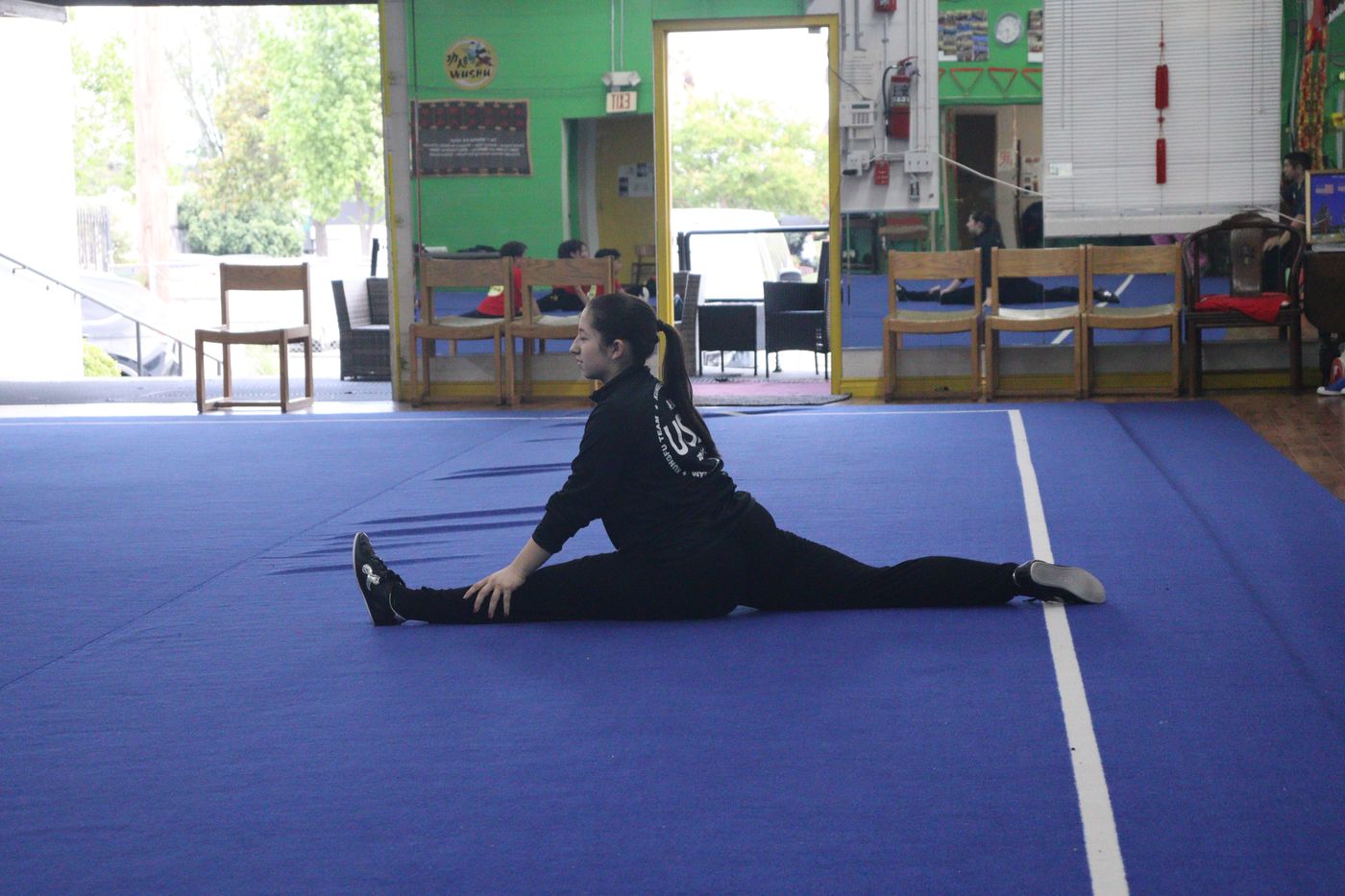 An adult student holding a full side split on the training mat