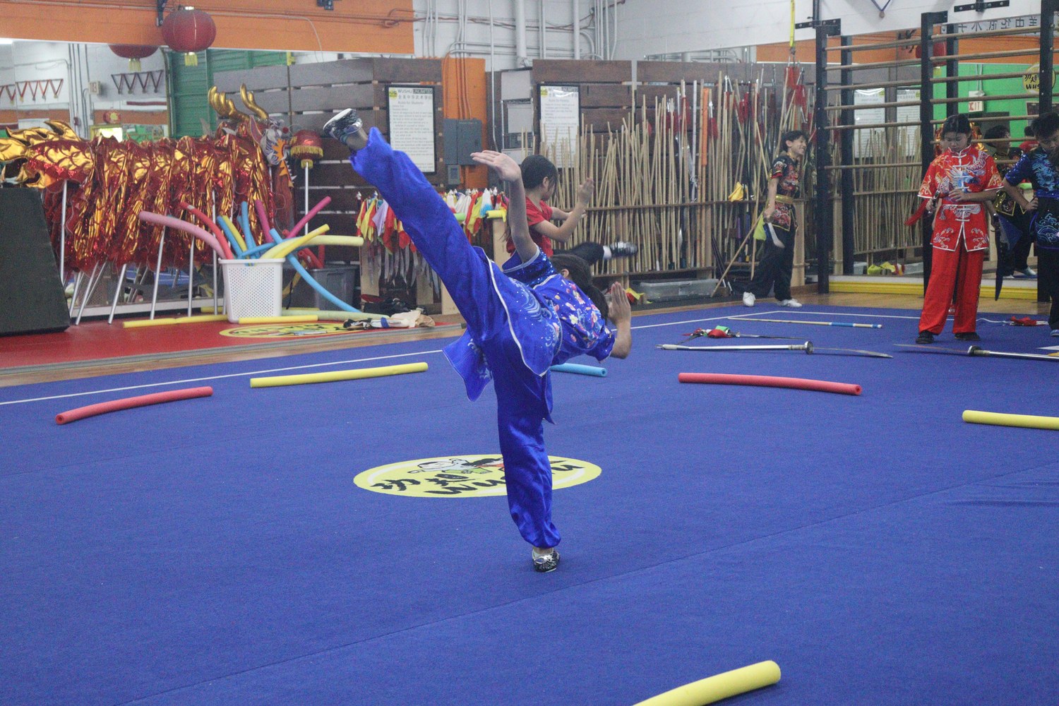Student in blue competition silks executing a high kick