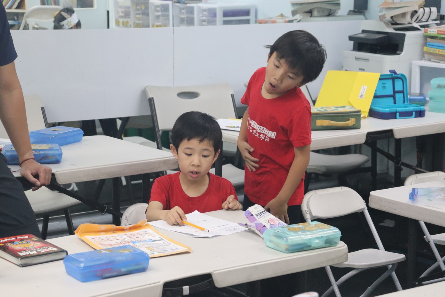 Children working at tables with an adult helping