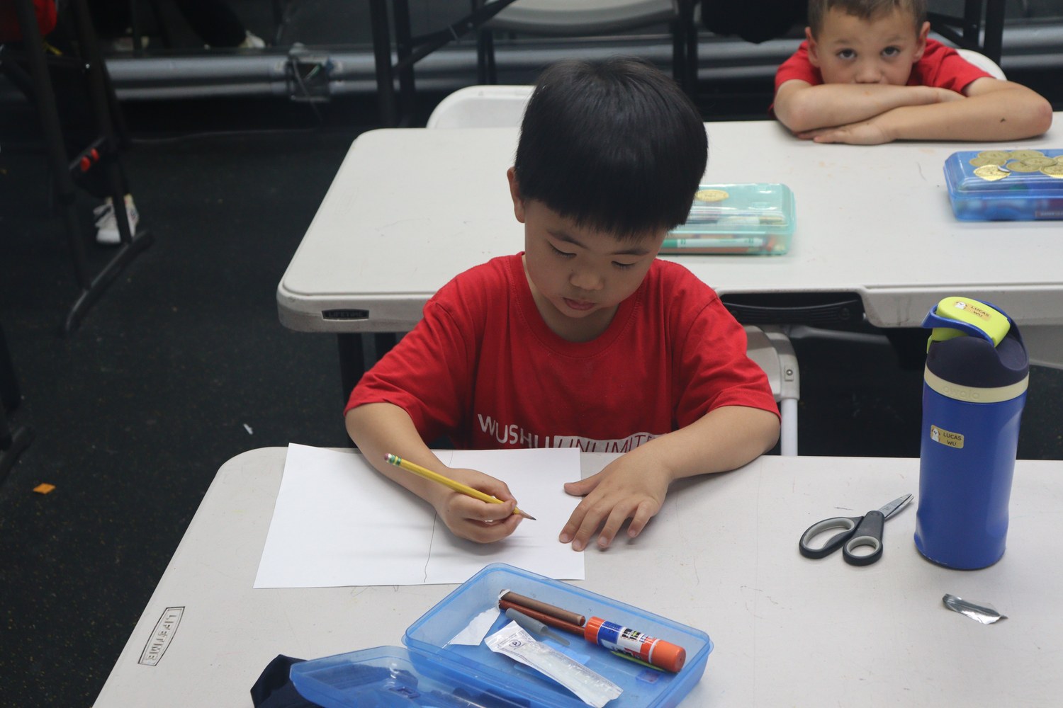Boy in a Wushu Unlimited shirt working at a desk