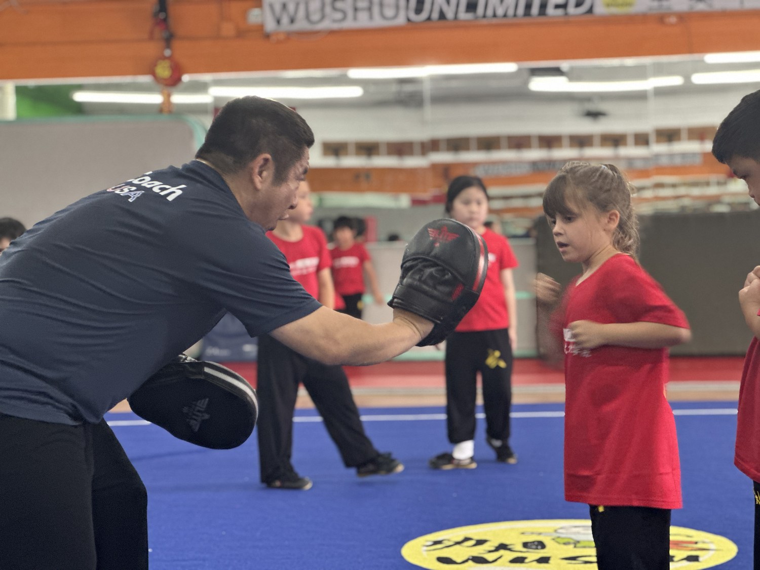 Coach holding a focus mitt for a young student
